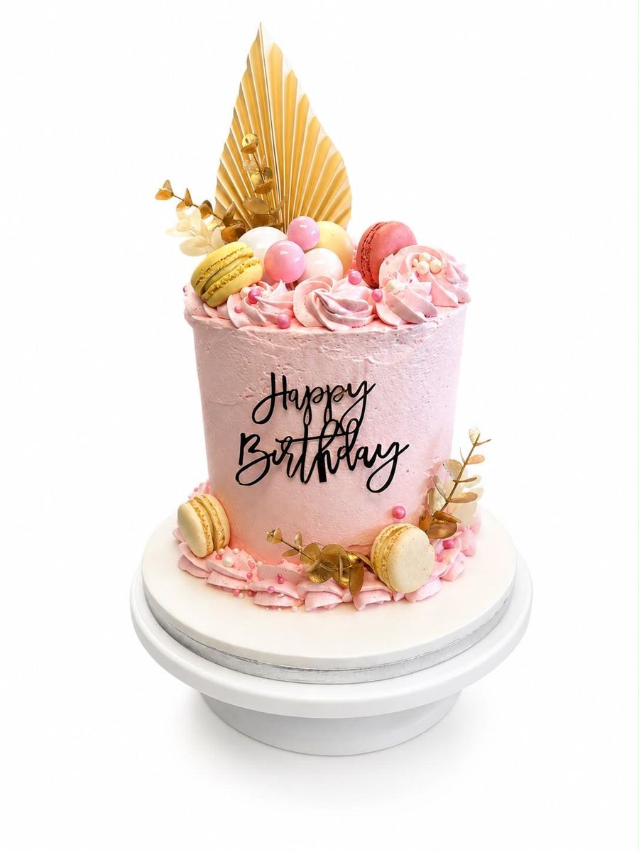 Pink buttercream birthday cake with macarons and gold decoration